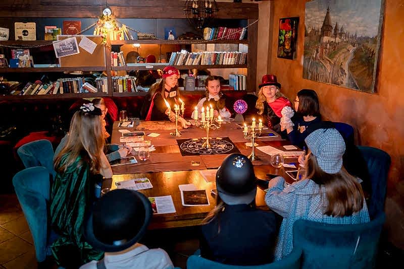 Дети разгадывают загадки в семейном квесте Хэллоуина в Алматы